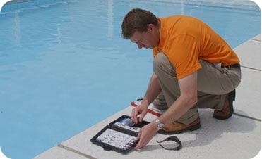 Man kneeling and inspecting a pool